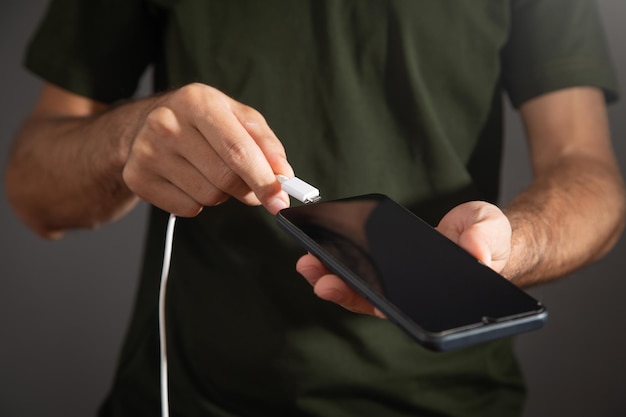 Man connecting charger cable to mobile phone