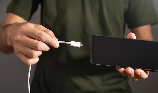 Man connecting charger cable to mobile phone