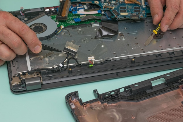 A man connects cables on the motherboard of the laptop