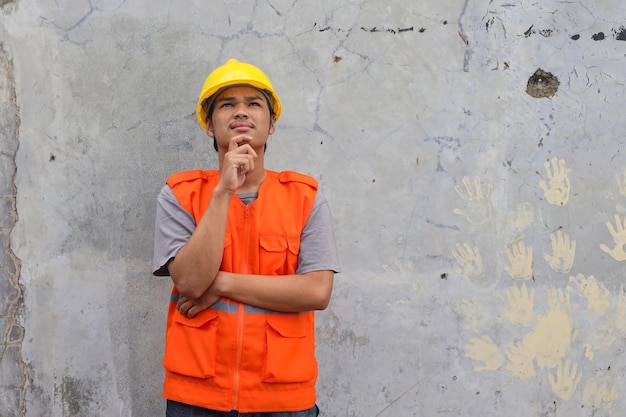 Man construction worker touches chin looking up thinks over new idea for building works as repair