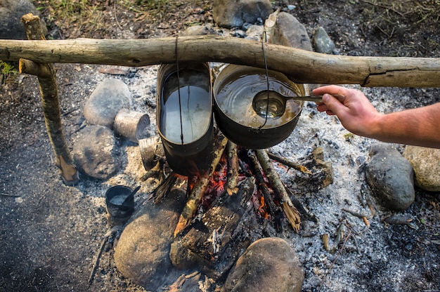 Man cooking in cauldrons outdoors