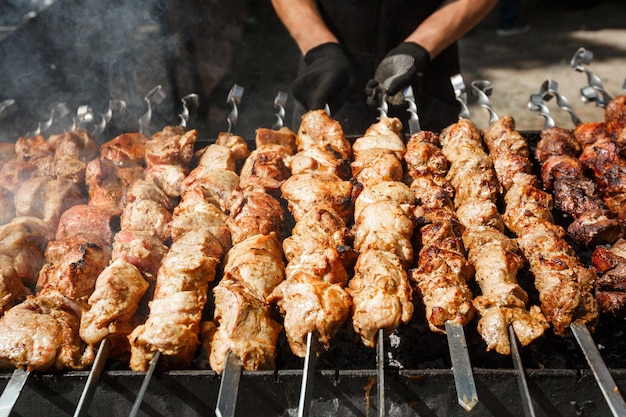 Man cooking grilled barbecue meet on skewer on coal grill