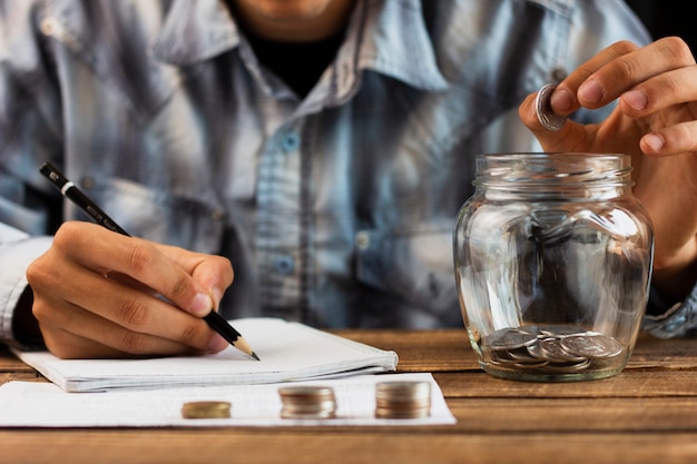 Man counting savings coin from jar