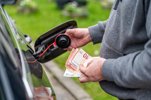 A man counts money standing at an open fuel tank the concept of rising fuel prices closeup