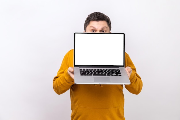 Man covering half of face with laptop with empty display for advertisement or promotional text