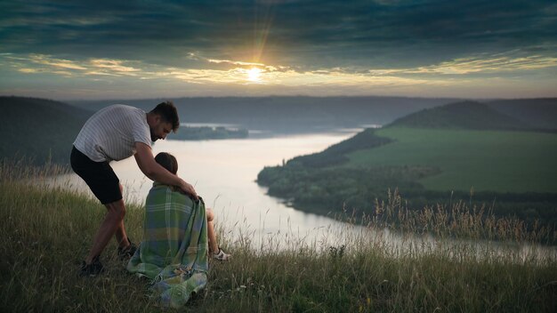 The man covering his woman with a plaid on the rainy sky background