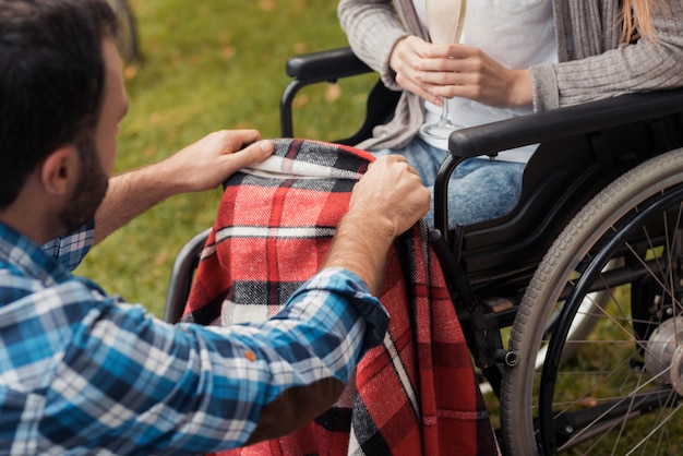 A man covers her legs with a blanket.