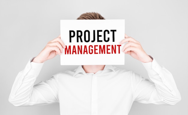 Man covers his face with a white paper with text Project Management