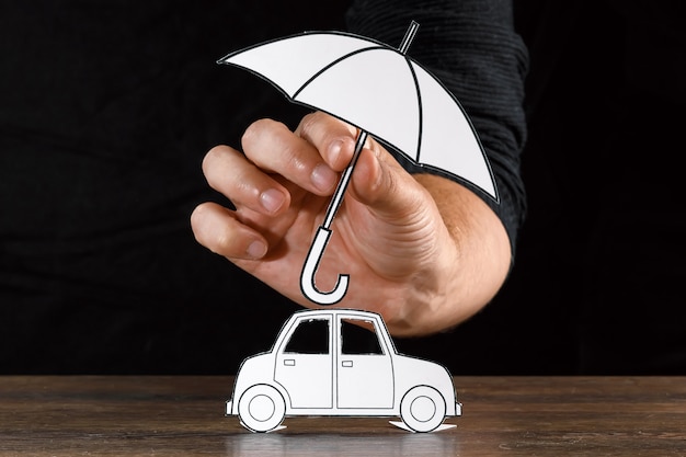 Photo man covers a paper car with paper umbrella