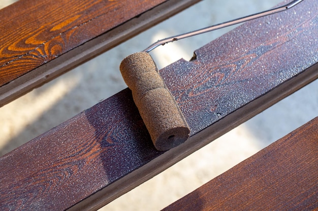 A man covers a wooden board with stain using a roller Hobby carpentry