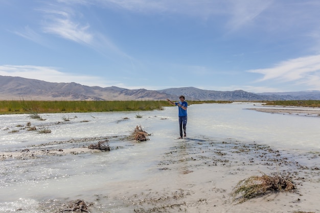 Man crosses a white mountain river on foot. Altai, Mongolia.