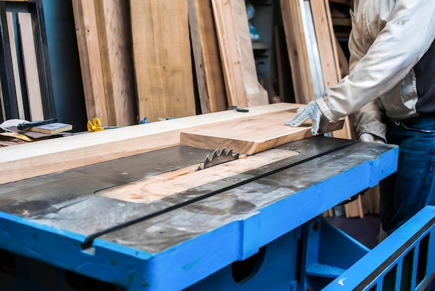 a man cuts a board on a stationary circular saw in a carpentry workshop