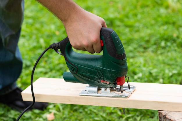 A man cuts a board with a jigsaw