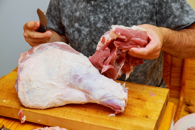 Man cuts of fresh piece of meat on a wooden cutting board the home kitchen