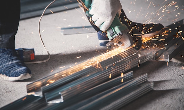 Man cuts metal profile with a grinder. Industrial concept