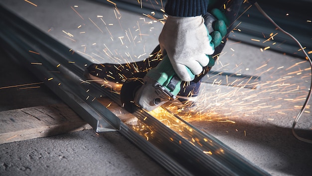 Man cuts metal profile with a grinder. Industrial concept