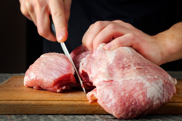 A man cuts a piece meat on a cutting board