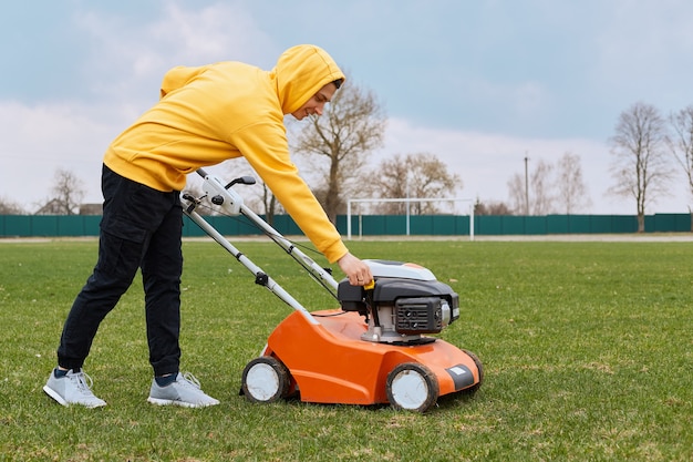 Man cutting green grass with lawn mower in backyard