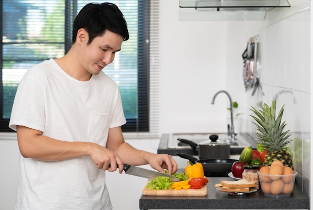 Man cutting vegetables for preparing healthy food in the kitchen at home