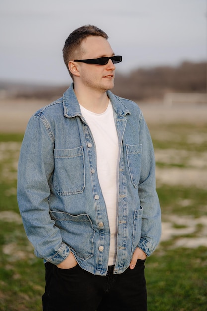 A man in a denim jacket stands in a field