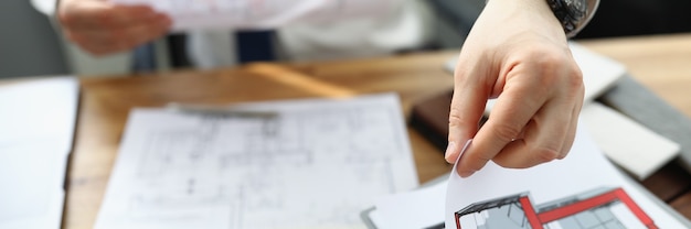 Photo man designer sitting at table and holding design project of apartment in his hands