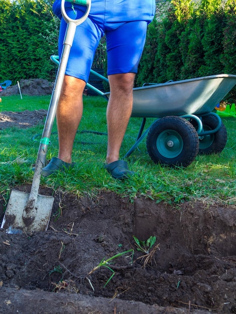 Man digging a garden for new plants and wheelbarrow in garden