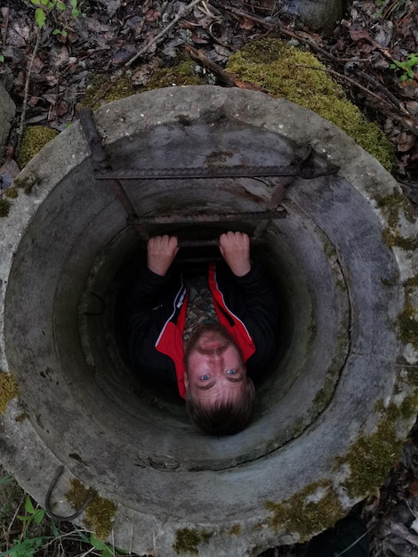 A man in a dirty water drain with a metal bar that says'the word " on it.