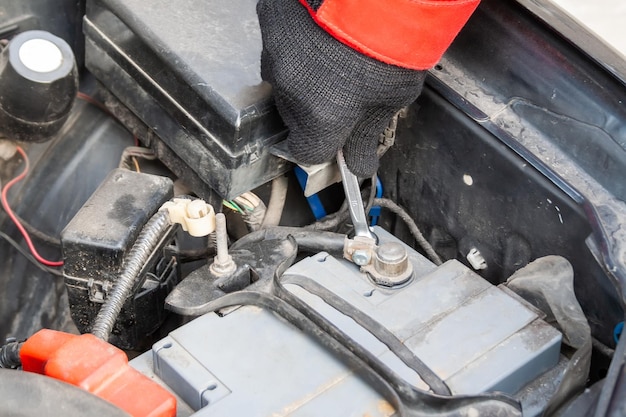 Man disconnecting the terminal on the car battery under the open hood of a Flatfour boxer car engine