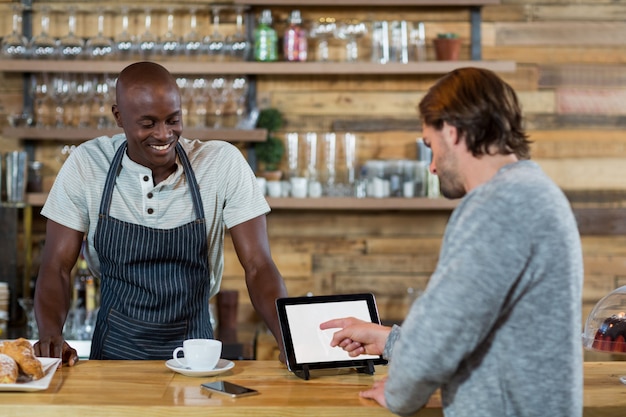 Man discussing over digital tablet with waiter