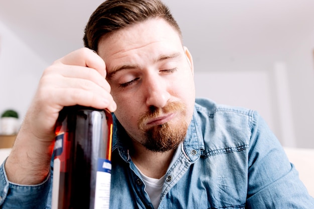 Man in Distress Holding Alcohol Showing Signs of Intoxication and Struggle