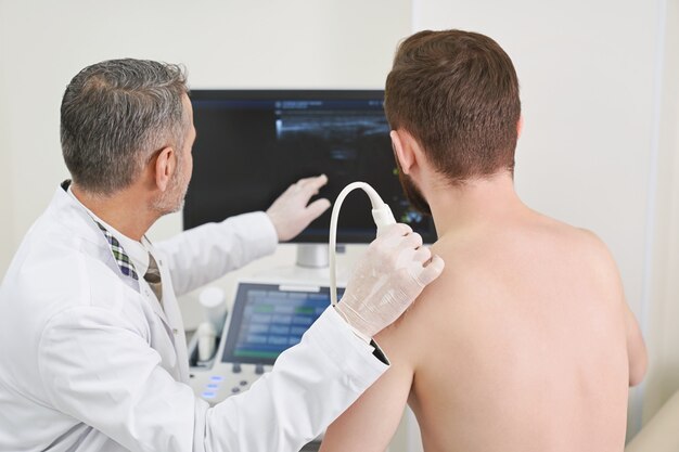 Man and doctor looking at screen, doing ultrasound check up