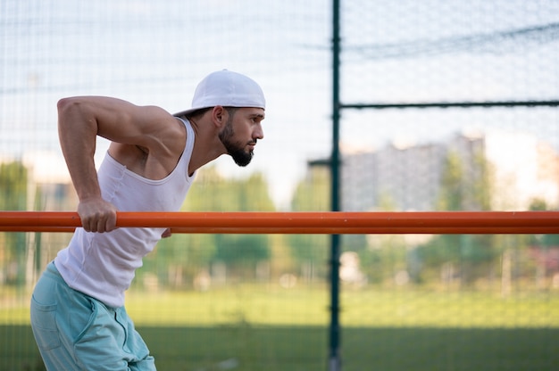 A man does push-UPS on the bars on the street during the day