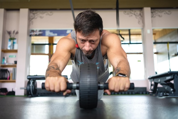 Man doing abs using a roller in the gymnasium