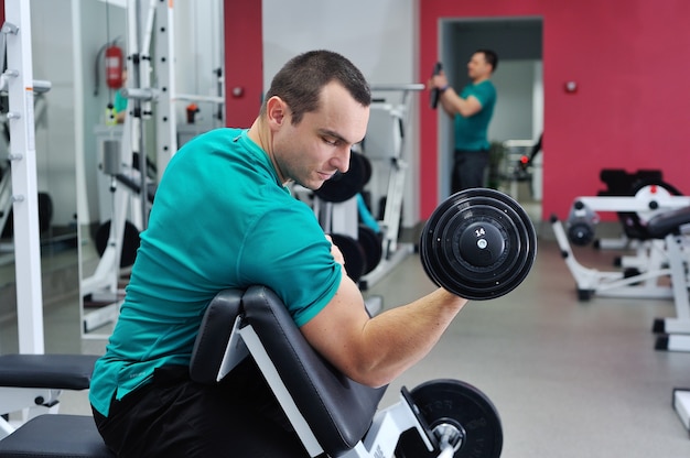 Man doing biceps exercise on scott bench with dumbbell