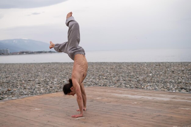 Photo man doing handstand at beach