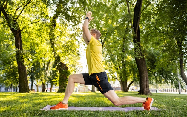 Man doing morning yoga at park outdoors in summer time guy exercising and stretch his body at nature