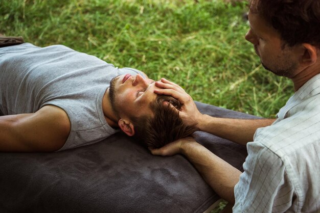 Man doing osteopathic head and neck massage in nature 4