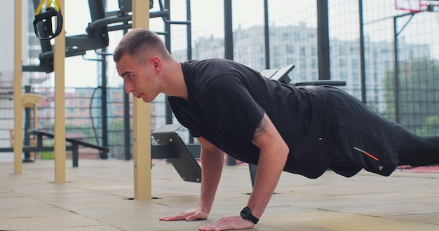 Photo man doing push up exercises on sports ground concept of healthy lifestyle outdoors gym