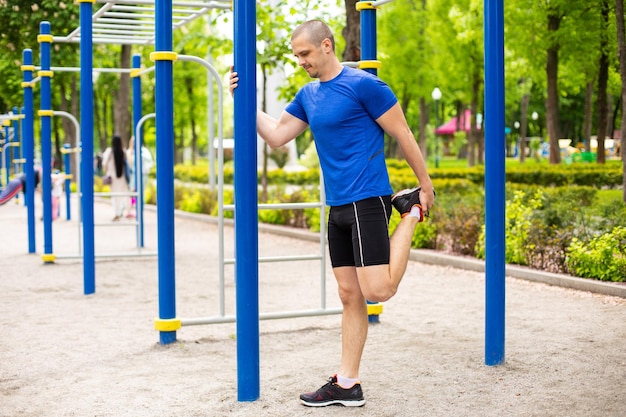 Man doing stretching after run workout in the park. Outdoor after training legs stretching