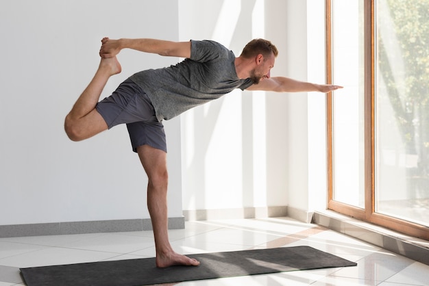 Man doing yoga indoor looking through window