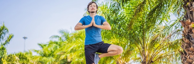 Man doing yoga in a tropical park banner long format