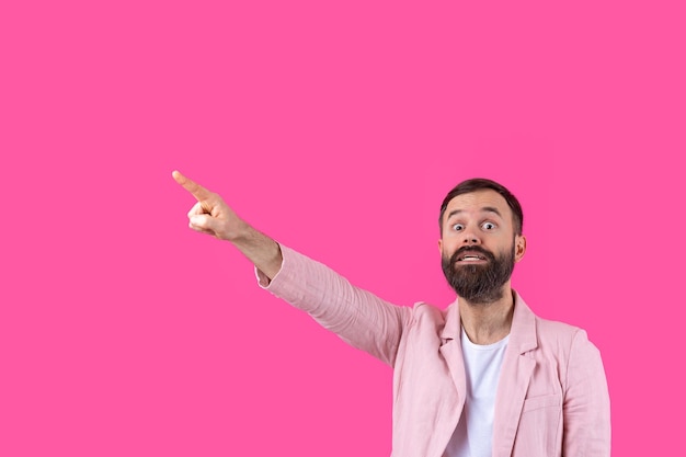 A man dressed in a pink jacket indicates the direction on a pink isolated background