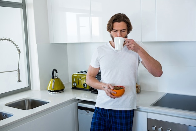 Man drinking coffee while having breakfast in kitchen