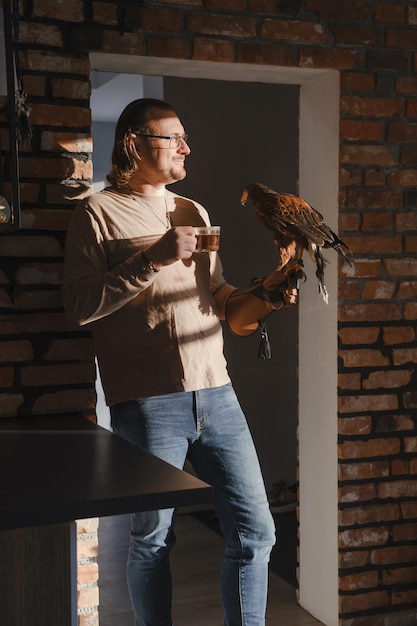 Man drinking coffee with wild bird at home on sunny kitchen