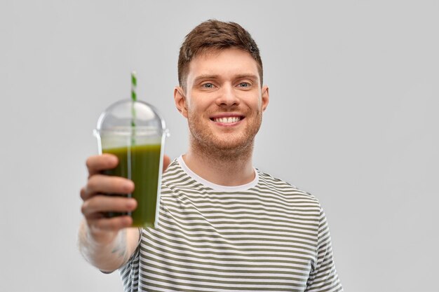 Photo man drinking green smoothie from disposable cup