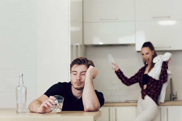 man drinks while sitting at a table in the kitchen