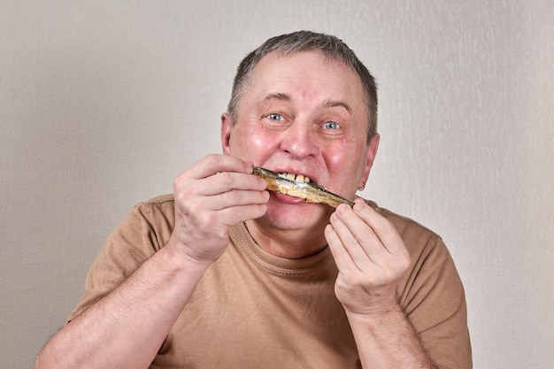 Man eating fried smelt fish holding fish with hands in front of face