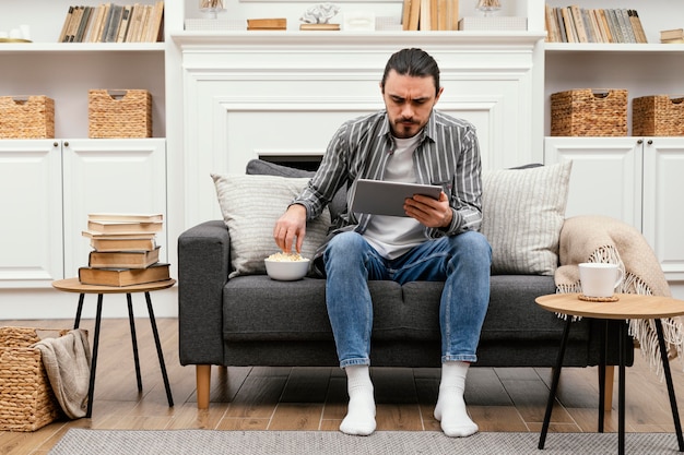 Man eating popcorn and holding a digital tablet