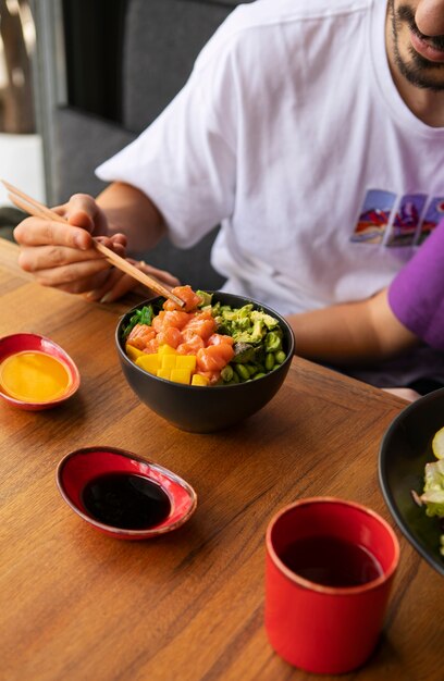 Photo man eating salmon dish bowl at the restaurant