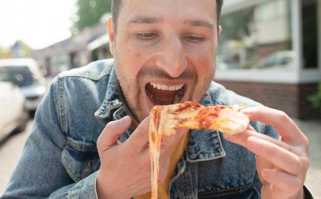 Photo a man eating a slice of pizza